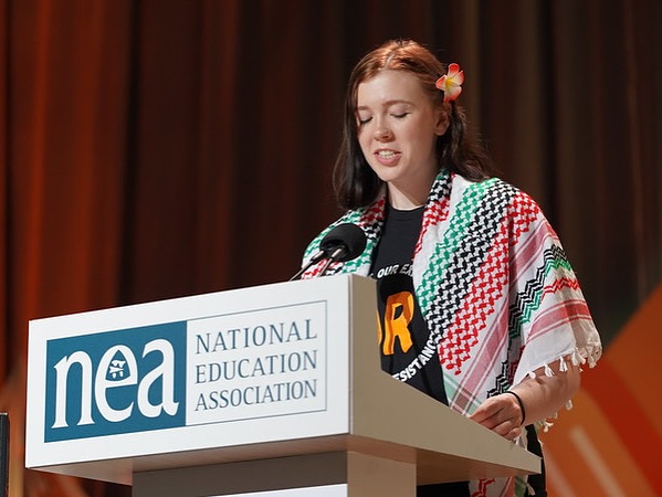 Hannah Speaking at a NEA Conference wearing a keffiyeh. 